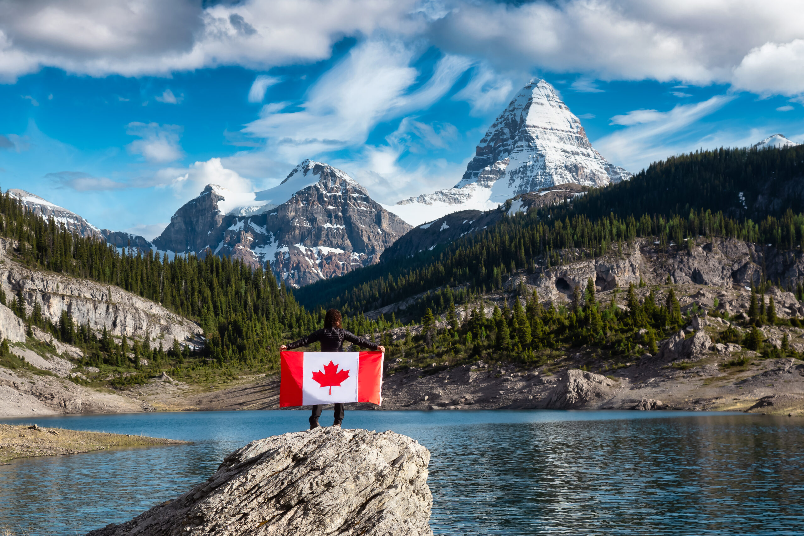 Girl Holding a Canadian National Flag. View of Og Lake in the Iconic Mt Assiniboine Provincial Park near Banff, Alberta, Canada. Mountain Landscape